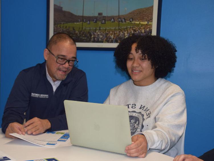 Student and staff member looking at laptop computer